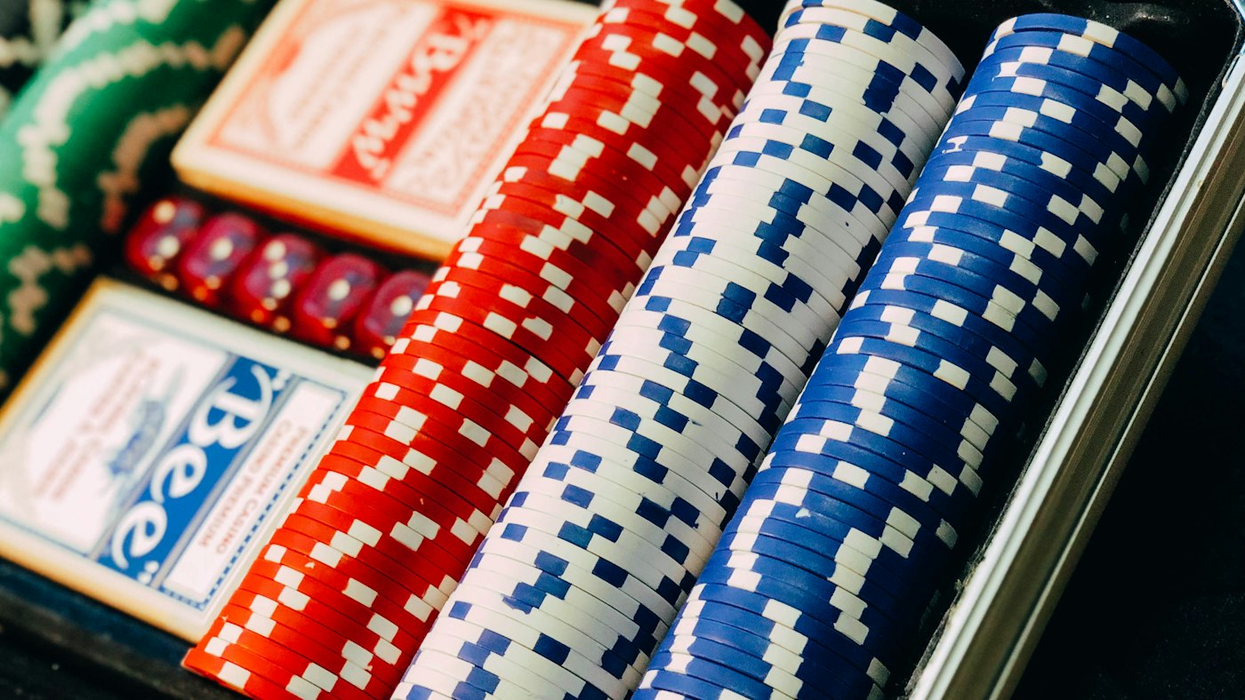 Fichas de póker rojas, blancas y azules junto a una baraja de cartas